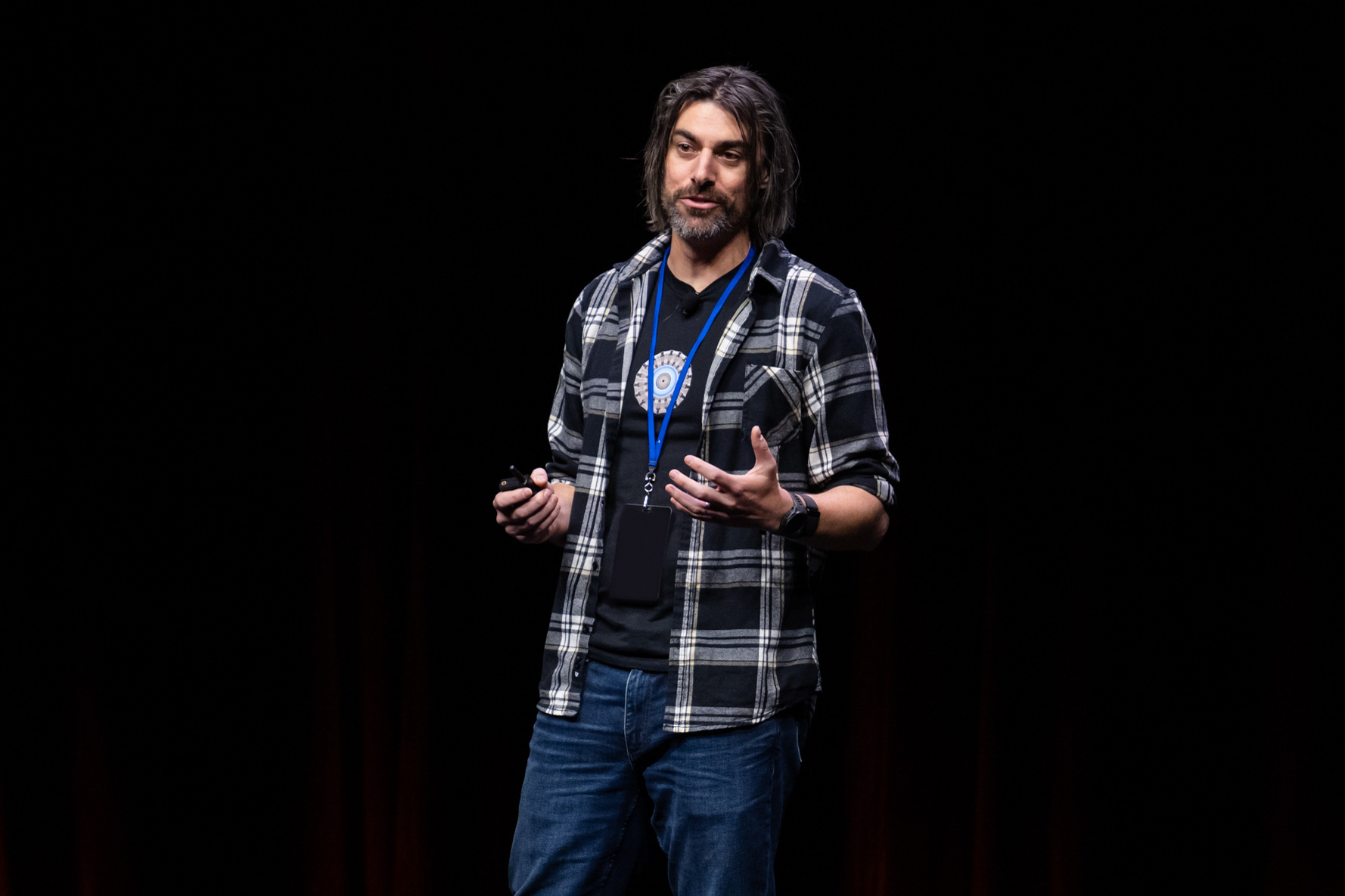 CFS Chief Science Officer Brandon Sorbom, wearing a plaid shirt and jeans, speaks on a stage in front of a dark black curtain